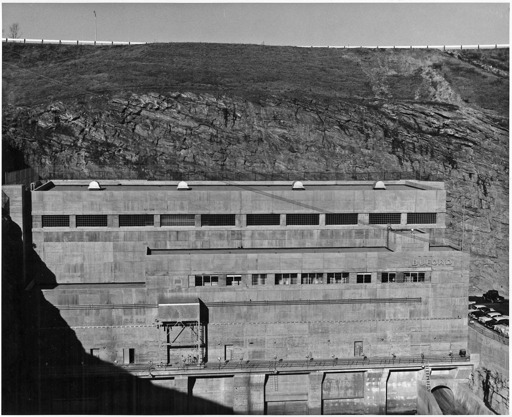 The Buford Dam Power Station is a hydroelectric power plant located on the Chattahoochee River in Buford, Georgia. It was built by the United States Army Corps of Engineers between 1950 and 1956 as part of the Buford Project for flood control, drinking water, and hydroelectric power generation. The dam is 1,785 feet (544 m) long and 190 feet (58 m) high. It impounds Lake Lanier, a 69,000-acre (28,000 ha) reservoir. The dam is named for the city of Buford, which was inundated by the reservoir.

The power plant has three Francis turbines with a total generating capacity of 126 megawatts (MW). The turbines are powered by water that is released from the dam and flows through the penstocks. The water is then returned to the Chattahoochee River below the dam.

The Buford Dam Power Station is a significant piece of infrastructure that provides clean, renewable energy to the region. The power plant is also a popular tourist destination and a great place to enjoy the outdoors.

Here is a timeline of the history of the Buford Dam Power Station:

1946: The U.S. Congress authorizes the construction of Buford Dam on the Chattahoochee River.
1950: Construction on the dam begins.
1956: The dam is completed and Lake Lanier begins to fill.
1958: The power plant is completed and begins generating electricity.
1964: The first public boat ramps open on Lake Lanier.
1970: The Lake Lanier Islands Resort opens.
1976: The Lake Lanier Olympic Venue opens.
1996: The rowing and sprint canoe/kayak events for the 1996 Summer Olympics are held at the Lake Lanier Olympic Venue.
2007: A severe drought causes the water level in Lake Lanier to drop to its lowest level in history.
2009: The water level in Lake Lanier begins to recover from the drought.
2013: Lake Lanier reaches its full pool level for the first time since 2007.
2017: The Lake Lanier Olympic Venue is renovated and reopened to the public.
2022: The Buford Dam Power Station continues to generate clean, renewable energy for the region.